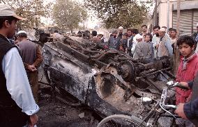 Residents look at wrecked Taliban vehicle